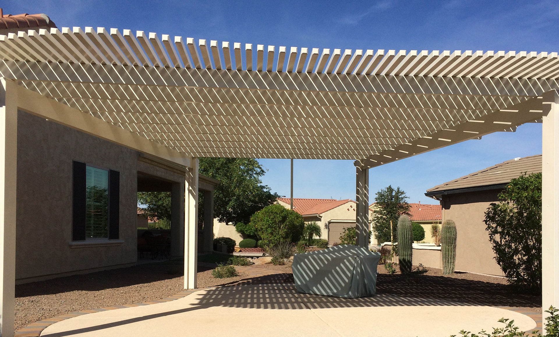 Tan wood-look aluminum pergola designed for low-maintenance coastal outdoor living